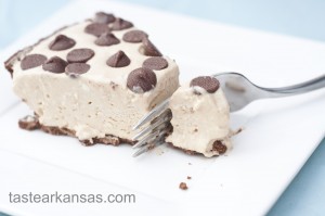 This photo shows a picture of no bake peanut butter pie being sliced into by a fork. The pie is light and fluffy, on a chocolate cookie crust with milk chocolate chips dotting the top of the pie.