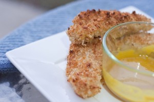 A crisp white plate of golden oven baked chicken tenders and a sweet honey mustard.