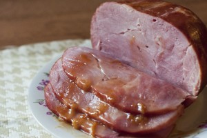 This photo shows a partially sliced ham from Petit Jean Meats with a drizzle of apricot glaze.
