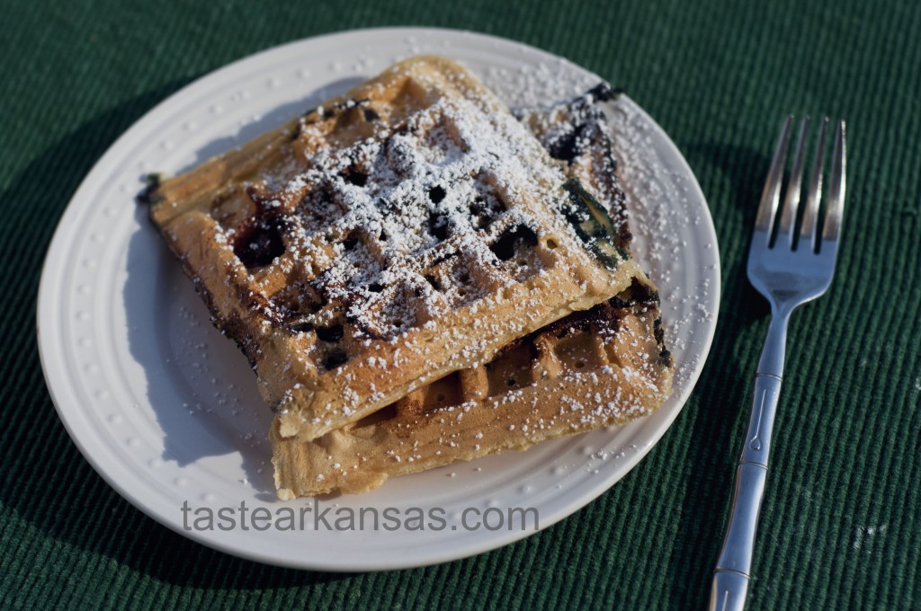 a warm plate of blueberry waffles with a dusting of powdered sugar