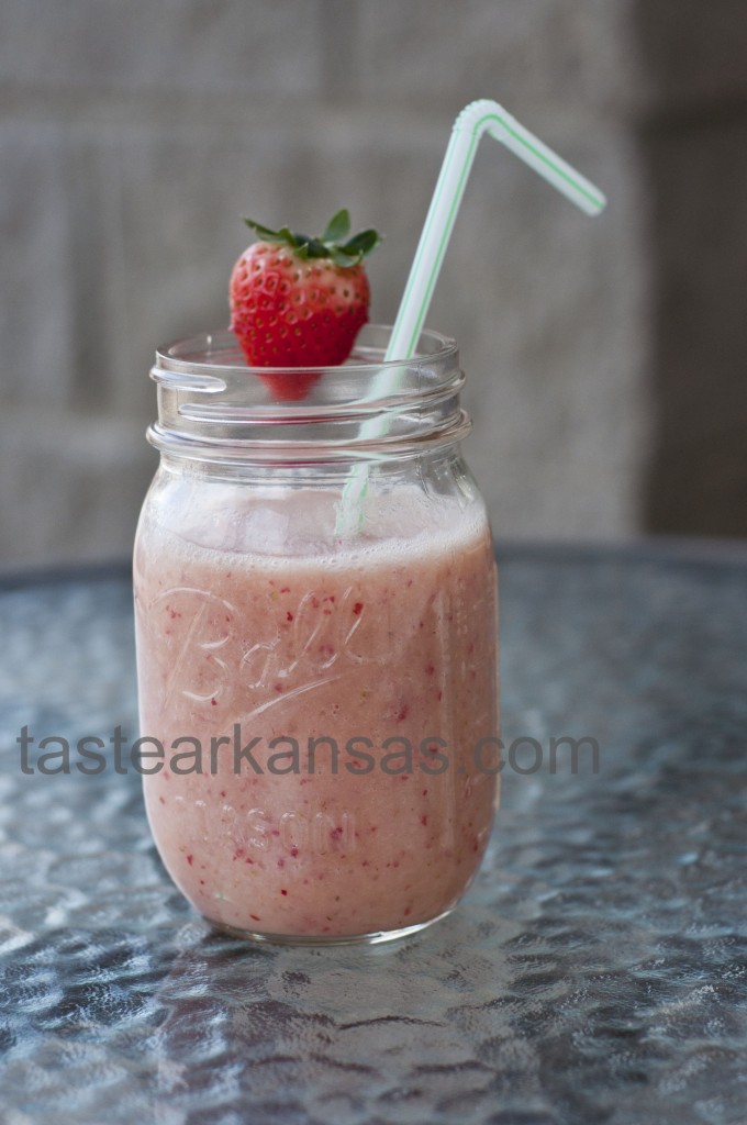 this photo is of a delicious strawberry banana smoothie in a mason jar with a strawberry garnish and striped straw