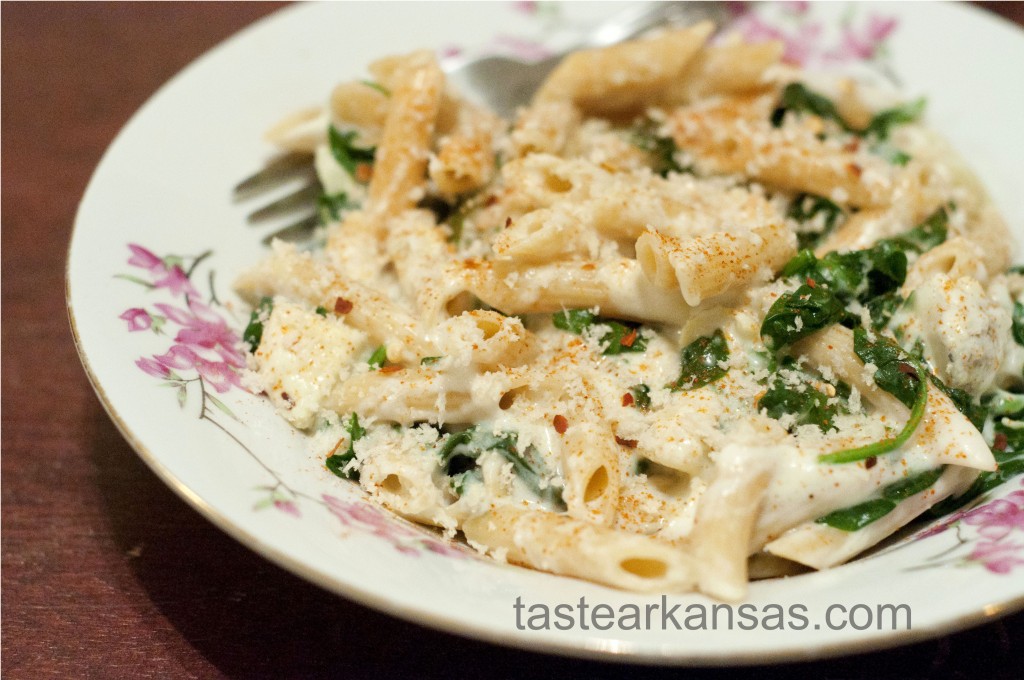 this photo is of a creamy, cheesy plate of spinach and artichoke pasta