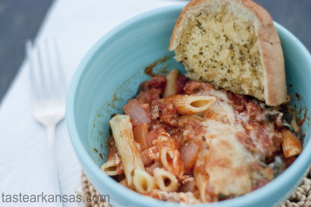 this photo is of a bowl of baked penne with a hunk of garlic bread 