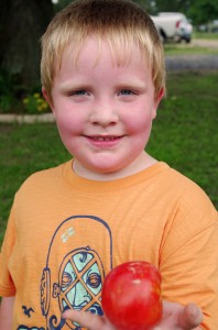 Tayden shows off one of the tomatoes he picked from the garden.